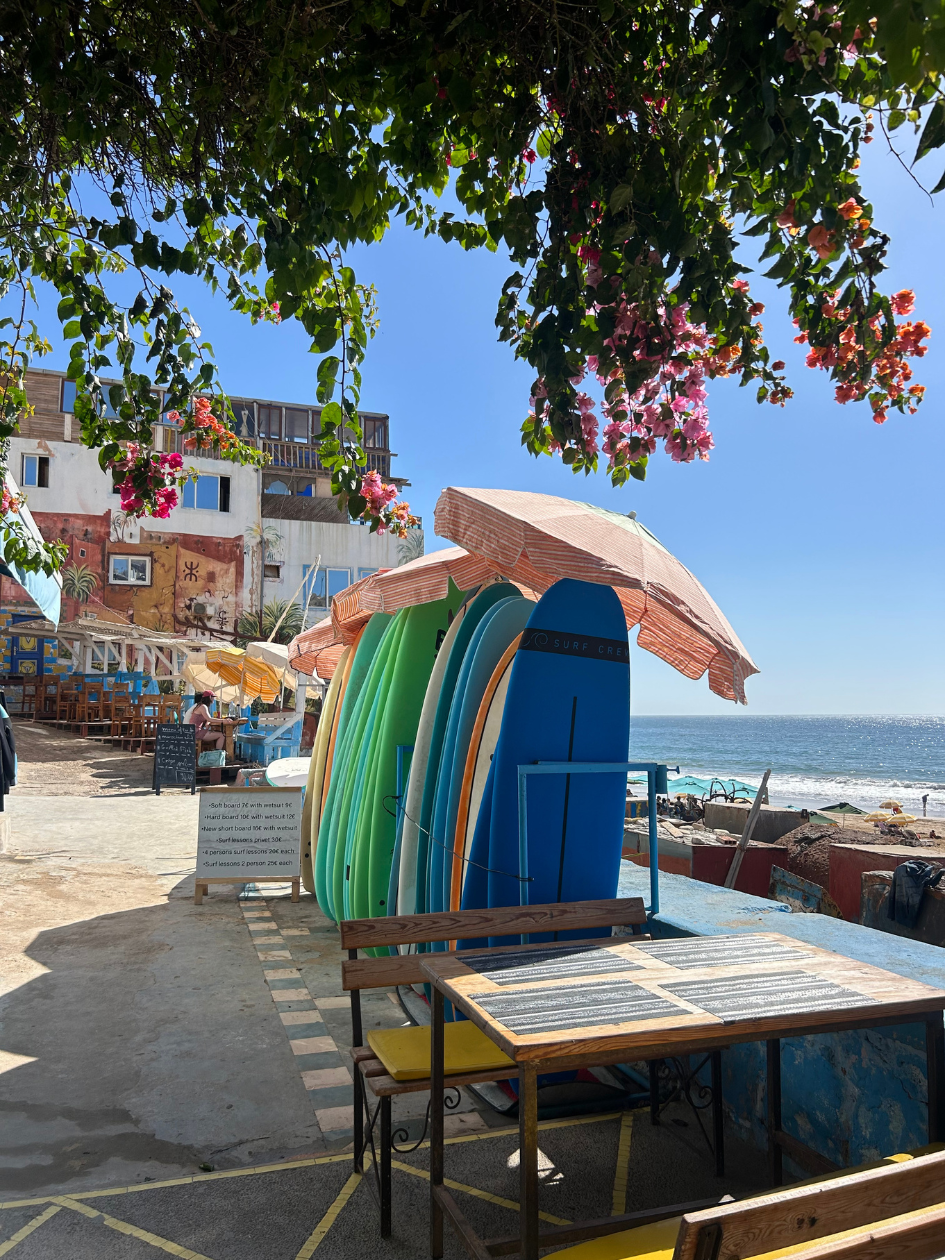 Surf deske pod oranžnimi senčniki ob plaži
